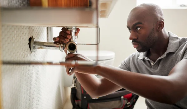 a male plumber fixing a pipe connection from Plumbing Lake Travis in Austin, TX Plumber near me